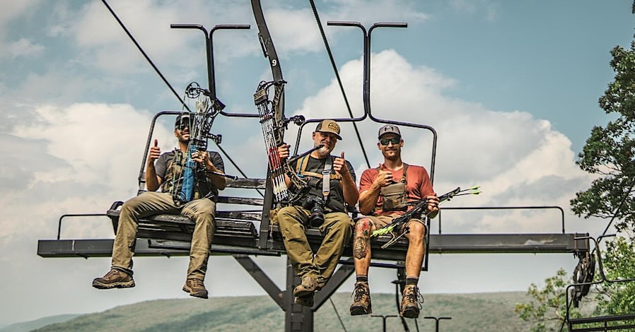 Three archers with compound bows riding the Arizona Snowbowl ski lift